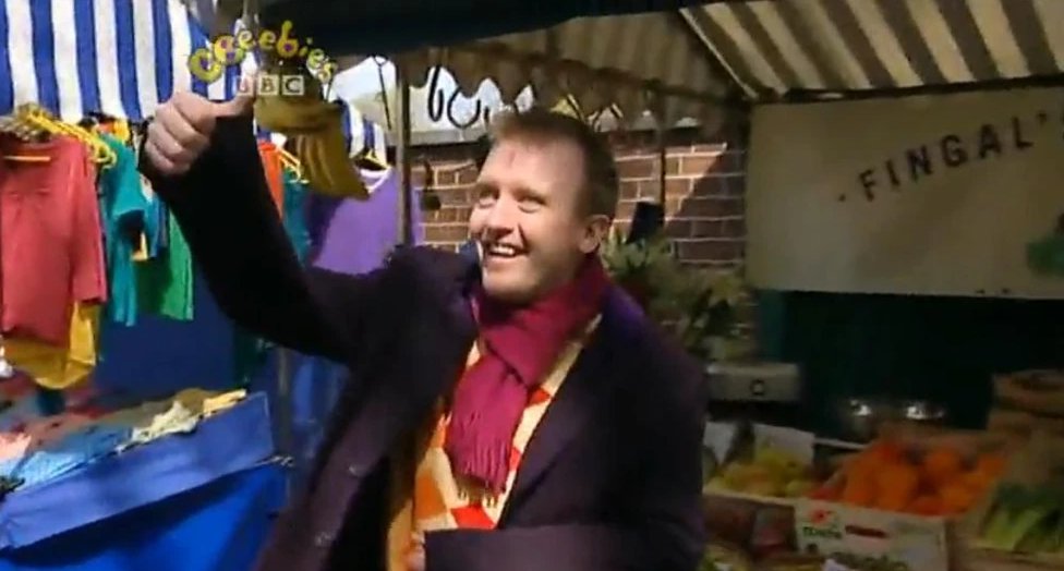 Chris McCausland as Rudi the market trader in Me Too! selling vegetables